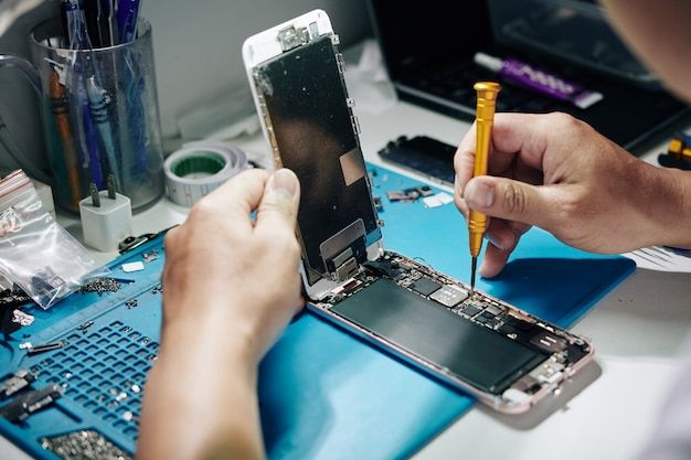 Técnico trabalhando em um smartphone aberto na bancada